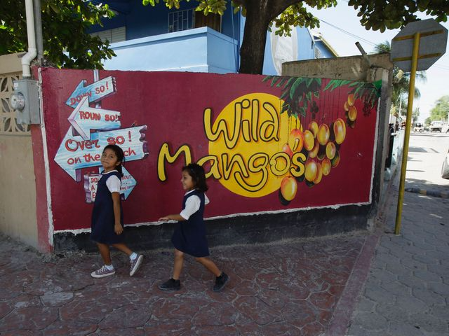 Schoolgirls walking past a mural in Belize